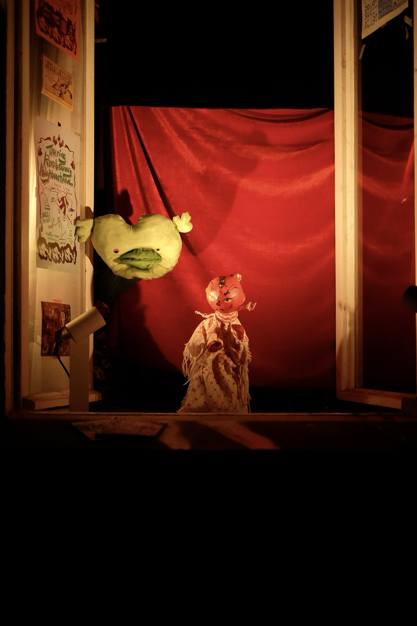 Handmade puppets performing before a red curtain